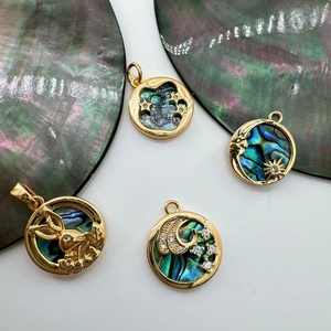 Macro view of 18K gold plated abalone shell charms featuring rabbit and celestial motifs