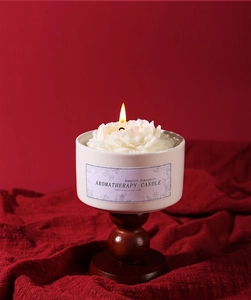 Close-up of a flower-shaped aromatherapy candle in a ceramic cup on a wooden base