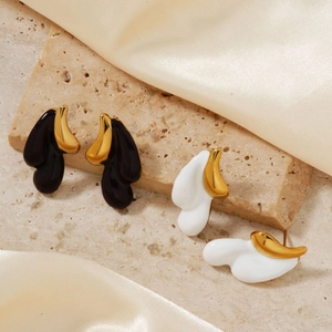 Detailed view of black and white teardrop earrings on textured beige stone