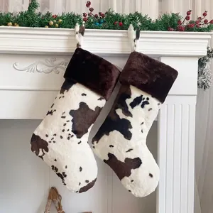 20-inch cow print Christmas stockings with plush faux fur trim hanging on fireplace mantel