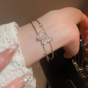 Macro detail of gold butterfly bracelet with pink and white zircon stones on model wrist
