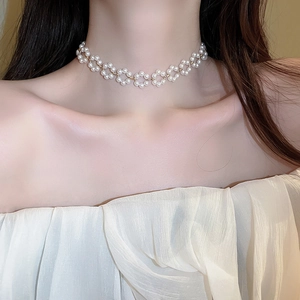 Gros plan d'un collier choker en perles avec motifs floraux blancs sur un mannequin