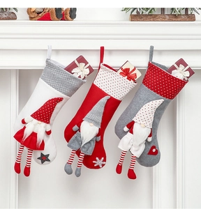 Close-up of three knitted Christmas stockings featuring Nordic gnome dolls on a white mantle