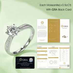 Moissanite ring with official GRA certificate and warranty card on green background