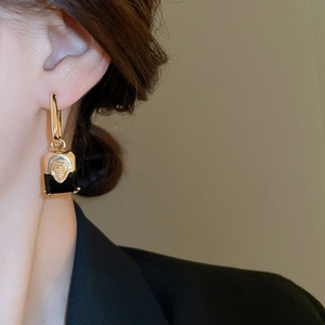 Detail of vintage gold lion head earring with black rectangular pendant on a model
