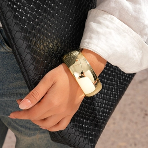 Detail of wide polished gold cuff bracelet on model with modern minimalist mirror finish