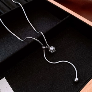 Detail showing silver snake chain necklace with round zircon pendant on black velvet tray