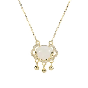 Close-up of golden Ruyi lock pendant with white chalcedony and small bells
