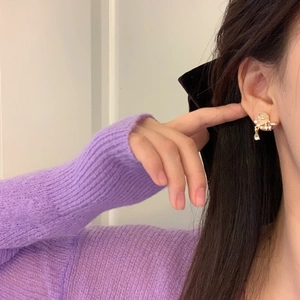 Detailed close-up of a floral rose clip earring with a water drop pendant on a model