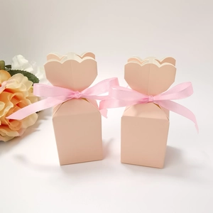 Close-up of light pink cardboard gift boxes with petal-shaped tops and ribbon bows