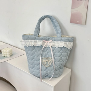 Dettaglio della borsa tote trapuntata azzurra con pizzo bianco e fiocco rosa
