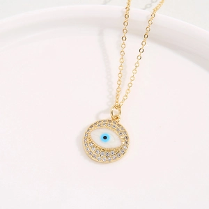 Close-up of golden evil eye pendant necklace with blue enamel and crystal inlay detail