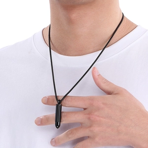 Close-up of a sleek black bullet pendant necklace worn by a model in a white t-shirt