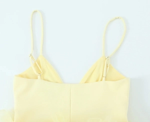 Detail van verstelbare dunne bandjes en de rugsluiting van een gele tule camisole