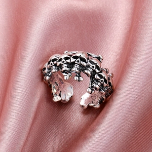Macro dell'anello teschio in stile punk finitura argento antico su raso rosa