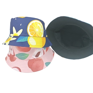 Detail of reversible bucket hats with blue lemon and pink peach fruit prints