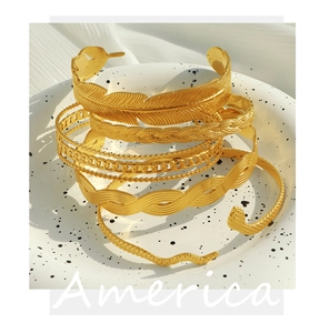 Macro view of assorted 18K gold plated chain bracelets and bangles on ceramic plate