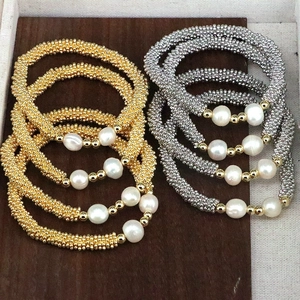 Detail of beaded pearl bracelets with gold and silver metallic beads on wood surface
