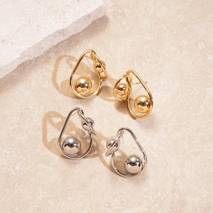 Minimalistische gedrehte geometrische Ohrstecker in Gold und Silber auf Stein-Hintergrund