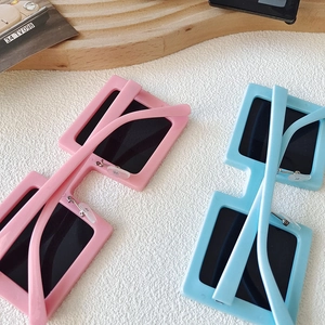 Detail of pink and blue square kids sunglasses on a white textured surface