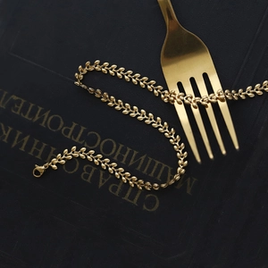 Detail view of gold wheat ear chain necklace with lobster clasp on a black vintage book