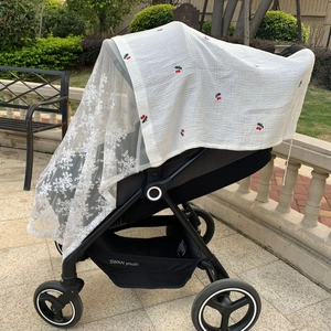 Outdoor side view of a black stroller with cherry print sunshade and lace mosquito net