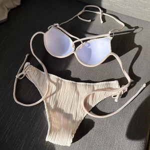 Detail of textured beige bikini fabric with drawstring ties and padded cups layout
