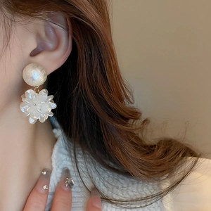 Gros plan de boucles d'oreilles fleur élégantes avec perles portées par un modèle