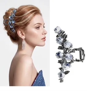 Detail of blue and white gradient camellia hair claw clip with dark metal leaves