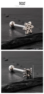 Macro detail of stainless steel tongue rings with snowflake and spider designs on dark stone