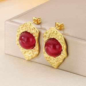Detailed side view of 18K gold plated rippled earrings with red cat eye stone inlay