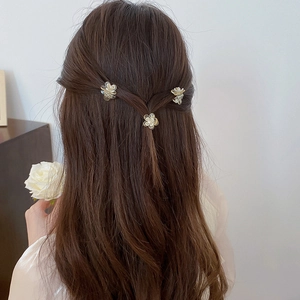 Close-up of three pearl white floral hair claws styled in a braided hairstyle for women