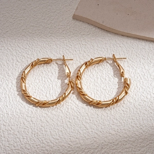 Macro detail of golden twisted rope texture on circular geometric hoop earrings