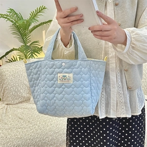 Close-up of light blue heart quilted handbag with Happy patch held by a model