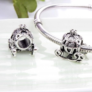 Close-up of silver pumpkin carriage charm on a snake chain bracelet with ornate crown detail
