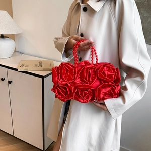 Detail of red silk rose evening bag with pearl bead handle held by a model
