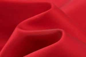 Vue détaillée du tissu satiné rouge montrant une texture lisse et un élégant drapé soyeux