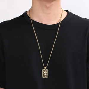 Detailed view of a gold gothic skull dog tag pendant with eye relief on a male model