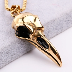 Detailed close-up of golden crow skull pendant in polished stainless steel finish
