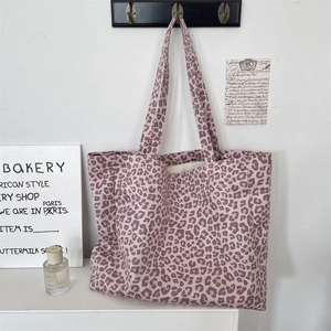 Detail of suede leopard print tote bag in soft pink hanging in a minimalist home setting