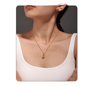 Detail of 18k gold heart lock necklace with turquoise inlay on a fashion model