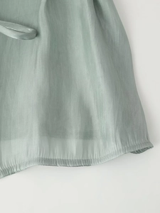 Detailed macro view of the glossy grey-green organza fabric hem with rolled edge finish