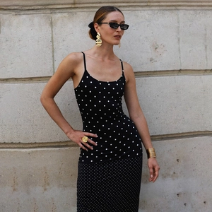 Detailansicht des schwarz-weißen Polka-Dot-Kleides an Model mit goldenem Schmuck