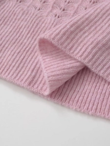Detail of soft pink knit sweater showing hollow texture and ribbed hem craftsmanship
