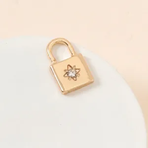 Close-up of a gold lock charm with a sparkling rhinestone star on a white pedestal