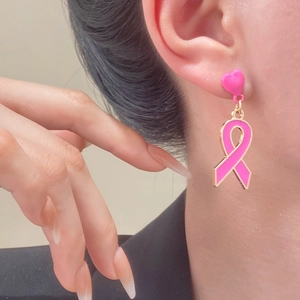 Nahaufnahme der rosa Schleifen-Ohrringe mit Goldrand und Herzstecker für Solidarität