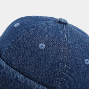 Macro shot of blue denim docker cap with stitched eyelets and fabric-covered top button