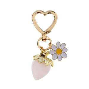 Detail of strawberry and daisy pendants on a golden heart-shaped keychain clasp