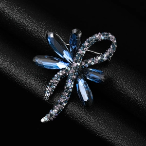 Macro view of crystal dragonfly brooch with blue teardrop wings and purple rhinestones