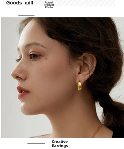 Close-up of a smooth 18K gold-plated teardrop stud earring worn by a model